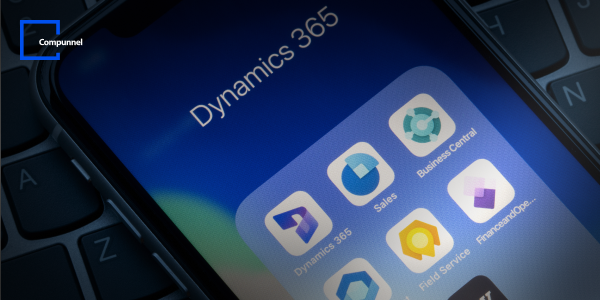 Close-up view of a smartphone screen displaying app icons for Dynamics 365, including 'Dynamics 365', 'Sales', 'Field Service', and 'Business Central', against the backdrop of a computer keyboard. The focus is on the Dynamics 365 app suite, suggesting the use of these applications for business solutions. The 'Compunnel' logo is visible in the top left corner, indicating the company's association with these business technologies.